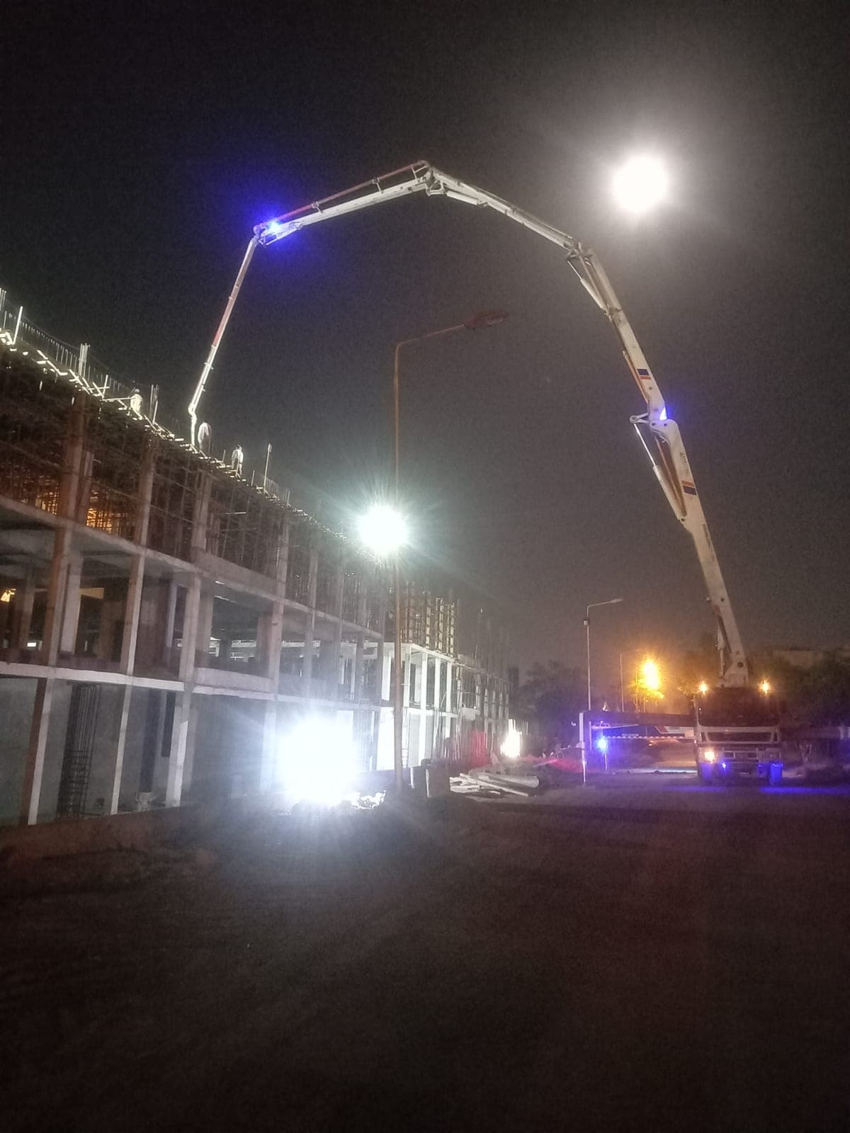 Night concrete pour with boom pump on a building frame