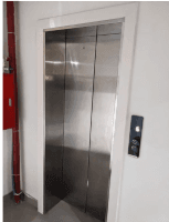 Stainless steel passenger lift doors with call panel in a building lobby