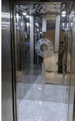 Passenger lift cabin interior with mirrored stainless steel walls and marble floor